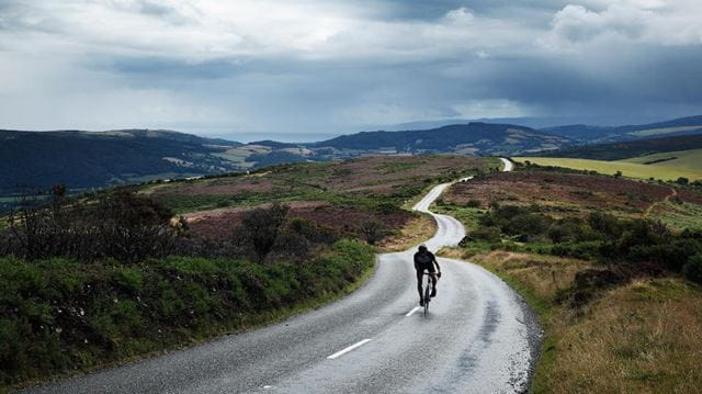 person cycling on road in countryside